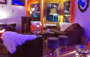een woonkamer met paarse meubels en een tafel met krukken bij VVF La Plagne Montchavin Paradiski in Bellentre