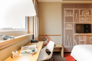 a hotel room with a desk and a bed and a tv at ibis Hotel München City in Munich