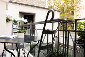 d'une table et de chaises noires sur le balcon. dans l'établissement Hôtel des Grands Hommes, à Paris