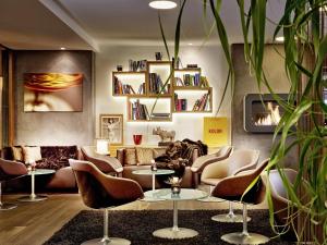 uma sala de estar com um sofá, cadeiras e mesas em AlpenParks Hotel & Apartment Taxacher em Kirchberg in Tirol