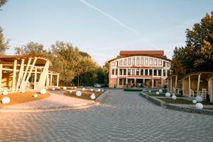 a large building with a brick courtyard in front of it at Hotel Merry Land in Horodenka