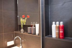 een badkamer met een plank met flessen zeep en bloemen bij HiP & STYLISCH B&B in Amsterdam
