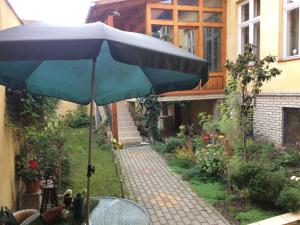 a table with a blue umbrella in a garden at Lyrius Vendégház - Debrecen in Debrecen +17 photos