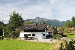 a white house with mountains in the background at Berg Blick Jugendherberge mit Privatzimmer in Kochel