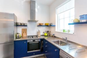 uma cozinha com armários azuis e um frigorífico de aço inoxidável em Watermans em Aldeburgh