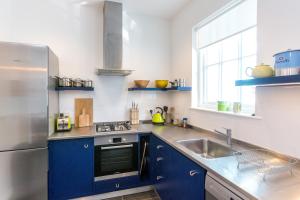 a kitchen with blue cabinets and a stainless steel refrigerator at Watermans in Aldeburgh