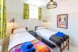 two twin beds in a room with yellow curtains at Watermans in Aldeburgh