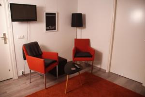 a room with two chairs and a flat screen tv at Bed and Breakfast de Verwennerij in Ermelo