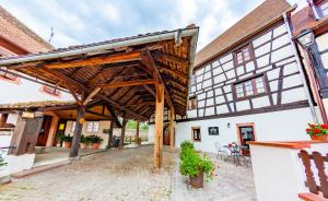 an old building with a large wooden pergola at Le gîte des Histoires in Kientzheim