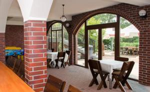 a dining room with tables and chairs and a brick wall at Hotel Nidzki in Ruciane-Nida