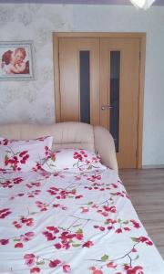 a bed with a white blanket with red flowers on it at Rooms in Apartment on Tbilisskiy bulvar 11 in Yekaterinburg