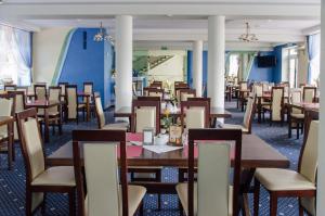uma sala de jantar com mesas e cadeiras de madeira em Hotel Nidzki em Ruciane-Nida