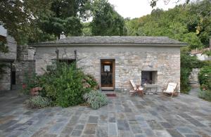 Casa de piedra con patio, mesa y sillas en Pelion Belvedere - The Modern Cottage, en Vizítsa