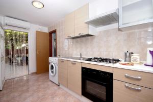a kitchen with a stove and a washing machine at Apartment Vesna in Premantura