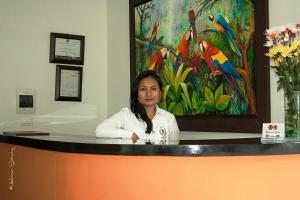 una mujer sentada en un mostrador con una pintura en Hotel Andinos Plaza Pitalito, en Pitalito