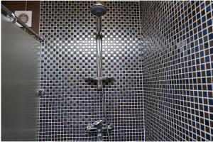 a shower in a bathroom with black and white tiles at Apartment on Pichugina in Karagandy