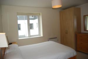 a bedroom with a white bed and a window at Harbour View Apartment Kinsale in Kinsale