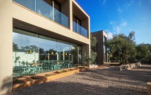 - une vue extérieure sur un bâtiment avec des fenêtres et des chaises dans l'établissement Cooking and Nature - Emotional Hotel, à Alvados