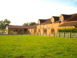 a large brick building with a green field in front of it at The Stables at the Vale in Yarm