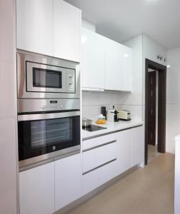 kuchnia z białymi szafkami i kuchenką mikrofalową w obiekcie Apartamento El Duque w Grenadzie