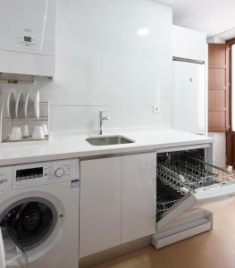 eine weiße Küche mit Geschirrspüler und Spüle in der Unterkunft Apartamento El Duque in Granada