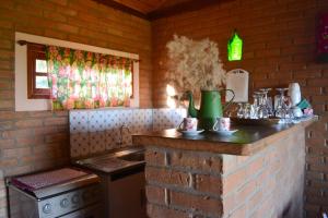 uma cozinha com uma parede de tijolos e um balcão com um lavatório em Ibitiaçu Chales em Conceição da Ibitipoca mais 35 fotografias
