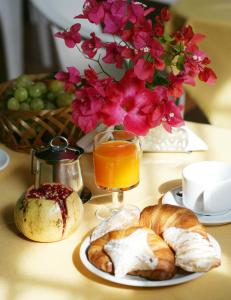 un tavolo con un piatto di pane e un bicchiere di succo d'arancia di Albergo Bouganville a Favignana