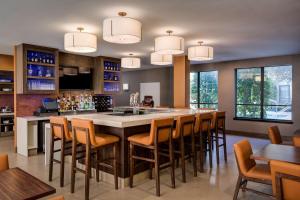 a large kitchen with a large bar with wooden chairs at Hyatt House Dallas Uptown in Dallas