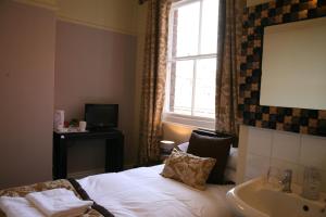 a bedroom with a bed and a sink and a window at Gillygate Guest House in York