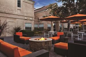 un patio avec un foyer extérieur, des tables et des parasols dans l'établissement Hyatt House Pleasanton, à Pleasanton