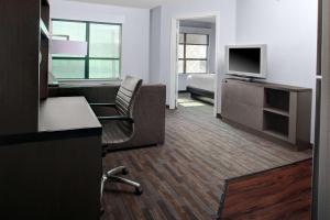 a hotel room with a bed and a desk with a television at Hyatt House Dallas Uptown in Dallas