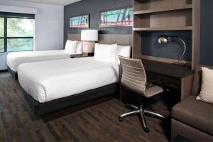 a hotel room with two beds and a desk and a chair at Hyatt House Dallas Uptown in Dallas