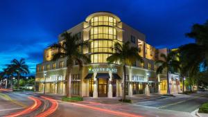 a building on a street with palm trees in front of it at Hyatt Place Delray Beach in Delray Beach