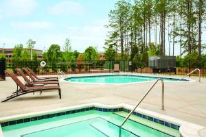 a swimming pool with two chairs next to at Hyatt Place Raleigh Cary in Raleigh