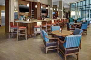 un restaurante con mesas y sillas y un bar en Hyatt Place Delray Beach, en Delray Beach