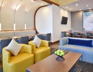 a waiting room with yellow chairs and a table at Hyatt Place Garden City in Garden City