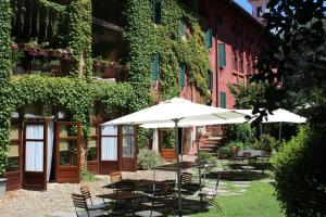 a patio with tables and chairs and an umbrella at Il Talucco B&B in Valdengo