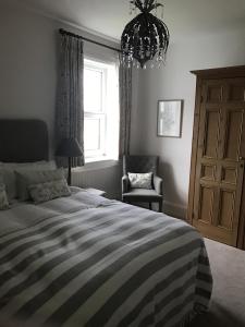 a bedroom with a bed and a chair and a chandelier at Old Vicarage Mortehoe Near Woolacombe 2 x sleeps 4 and 1 x sleeps 10 cottages in Mortehoe