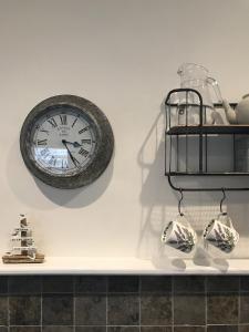 a clock on a wall with vases on a shelf at Old Vicarage Mortehoe Near Woolacombe 2 x sleeps 4 and 1 x sleeps 10 cottages in Mortehoe