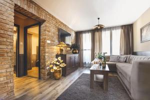 a living room with a couch and a brick wall at Komló Hotel Gyula in Gyula