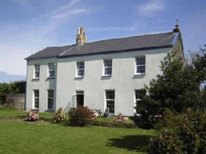 a large white house in a field of grass at Old Vicarage Mortehoe Near Woolacombe 2 x sleeps 4 and 1 x sleeps 10 cottages in Mortehoe