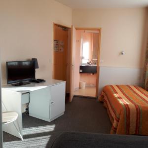 um quarto de hotel com uma cama e uma secretária com uma televisão em Le Saint Christophe em Cosne Cours sur Loire