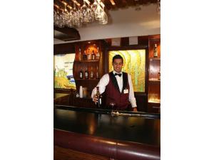 Ein Mann im Smoking steht hinter einer Bar. in der Unterkunft Hotel Gandara in Hermosillo