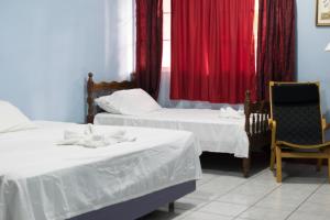 a room with two beds and a window with red curtains at Hotel Valerie in Managua