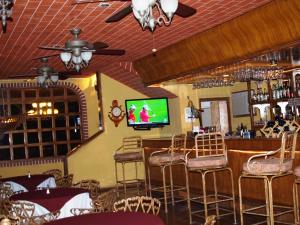 a bar with chairs and a television in a restaurant at Hotel La Hacienda de la Langosta Roja in San Felipe
