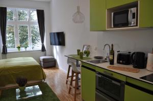 kuchnia z zielonymi szafkami i łóżko w pokoju w obiekcie Studio Apartments City&style w Zagrzebiu
