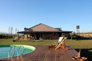 a wooden deck with a swimming pool and a house at Refugio Del Guira Guira in Los Reartes