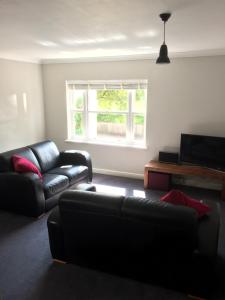 a living room with a black couch and a window at 3 Summertown Court in Oxford