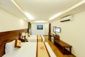 ein Hotelzimmer mit zwei Betten und einem Fernseher in der Unterkunft Sapa Lodge Hotel in Sa Pa