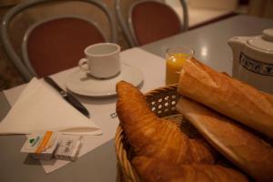 a basket of bread and a cup of coffee on a table at Hôtel des Pyrénées - Entre Bastille et Nation in Paris